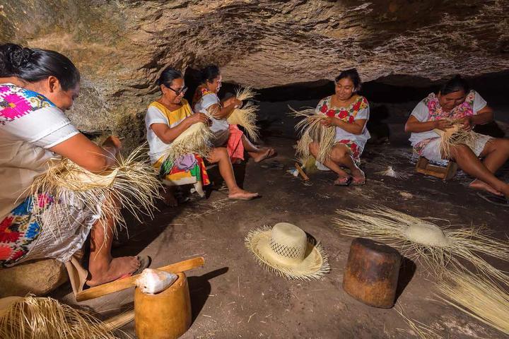 Cinco tejedoras trabajan la fibra de jipi en una cueva de Becal; a sus pies, sombreros a medio tejer.