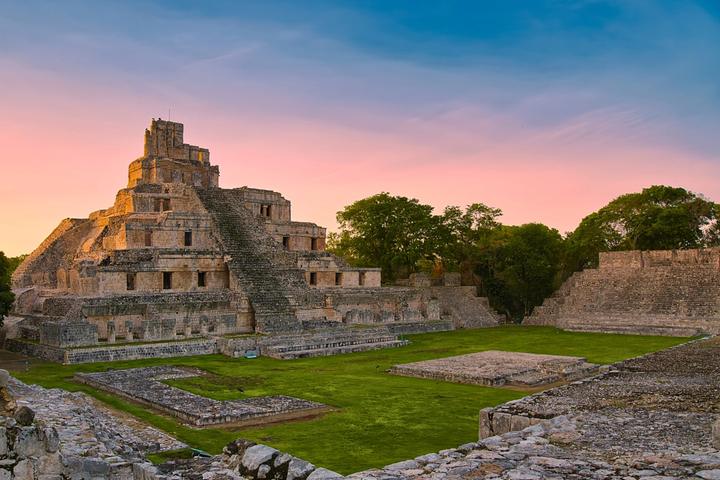 El Edificio de los Cinco Pisos de Edzná al atardecer, frente a una gran plaza de pasto.